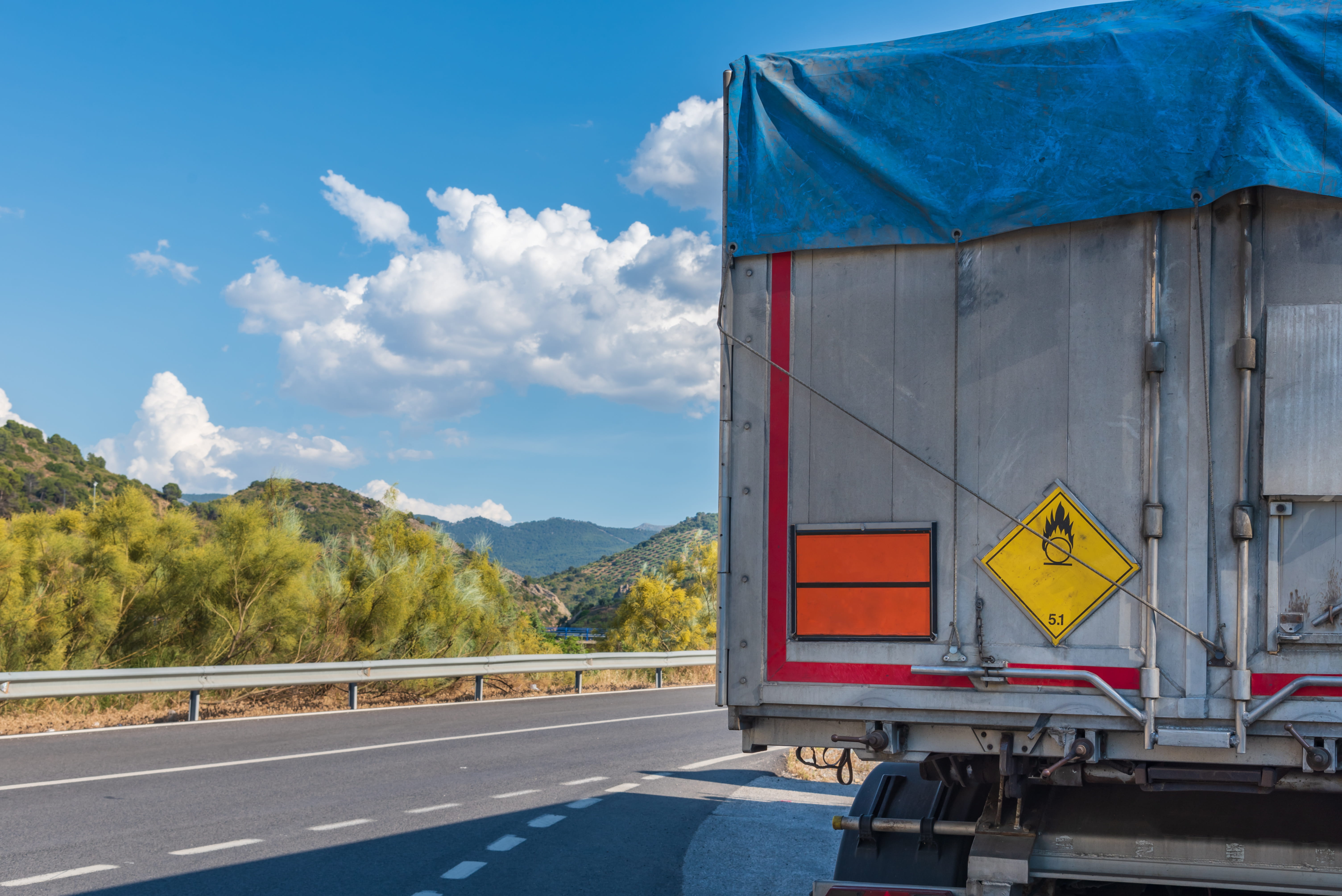 Baksiden av en trailer som er merket med farlig gods kjører på motorvei.